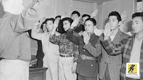 Januari 1943: Seorang perwira perekrutan infanteri di Pusat Relokasi Granada Colorado melantik sekelompok pemuda Nisei untuk bertugas di Angkatan Darat AS untuk bekerja sebagai penerjemah dalam bahasa Jepang tertulis dan lisan.