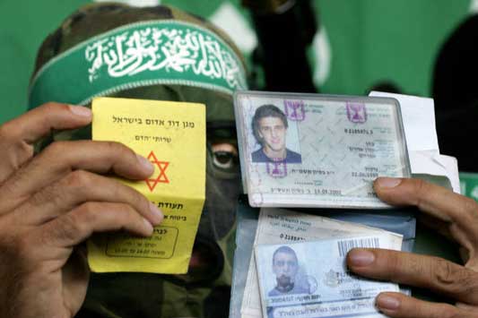 Di sini Abu Obeida memegang kartu identitas tentara "Israel" yang terbunuh setelah operasi mereka yang gagal untuk membebaskan Gilad Shalit.