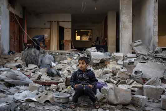 Seorang anak laki-laki Palestina duduk di atas reruntuhan bangunan yang hancur setelah serangan Israel di Rafah, Jalur Gaza selatan