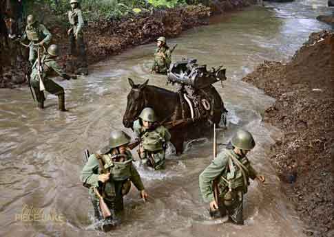 Awal 1942 – Prajurit KNIL mengarungi sungai di Jawa selama pertempuran untuk pulau utama kepulauan kolonial.